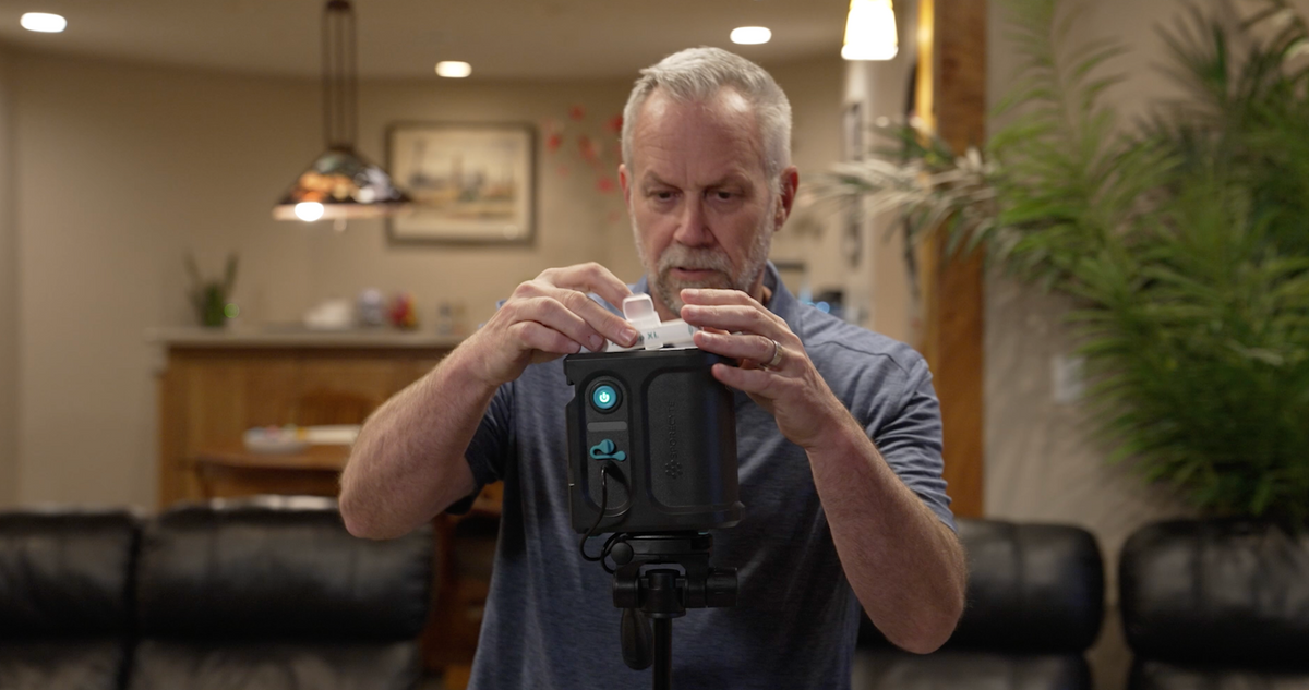 Air sampling pump with an AirTrap XL cassette on a tripod in a living room
